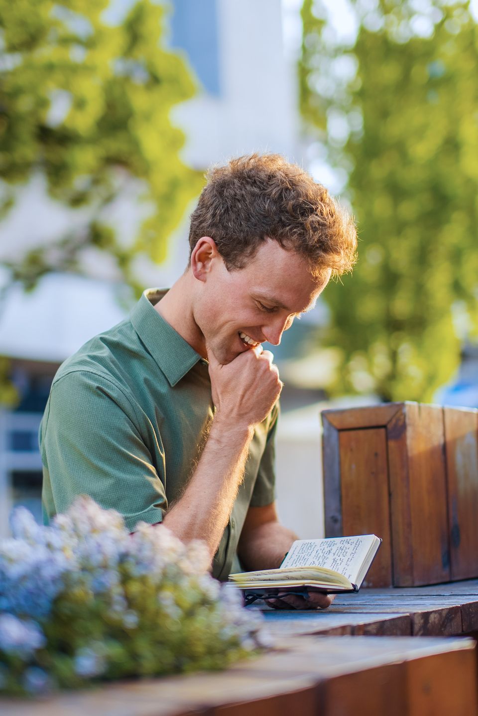 Blake Rupert laughing while reading a handwritten notebook outdoors
